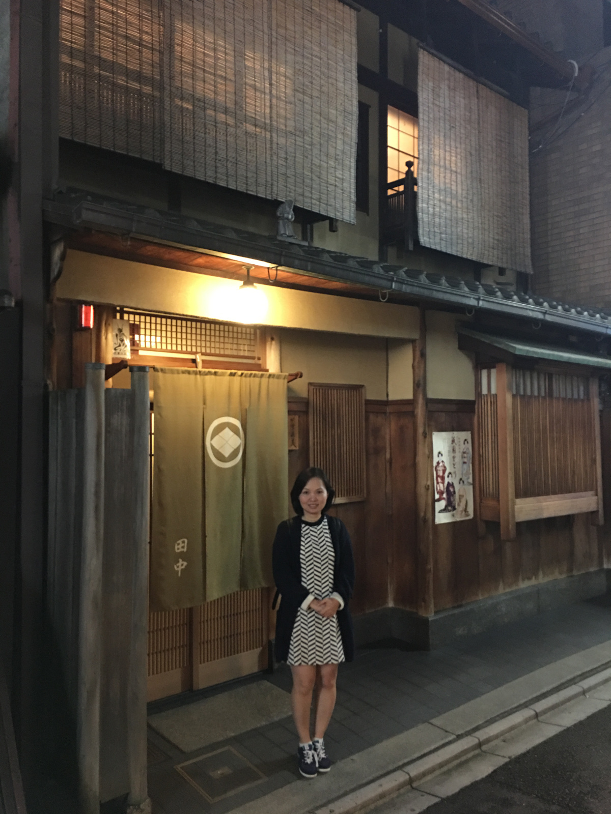 Asian woman standing in front of traditional wooden house in Kyoto, Japan