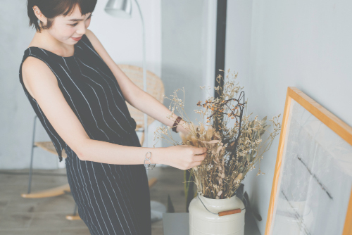 Asian woman arranging a flower in vase