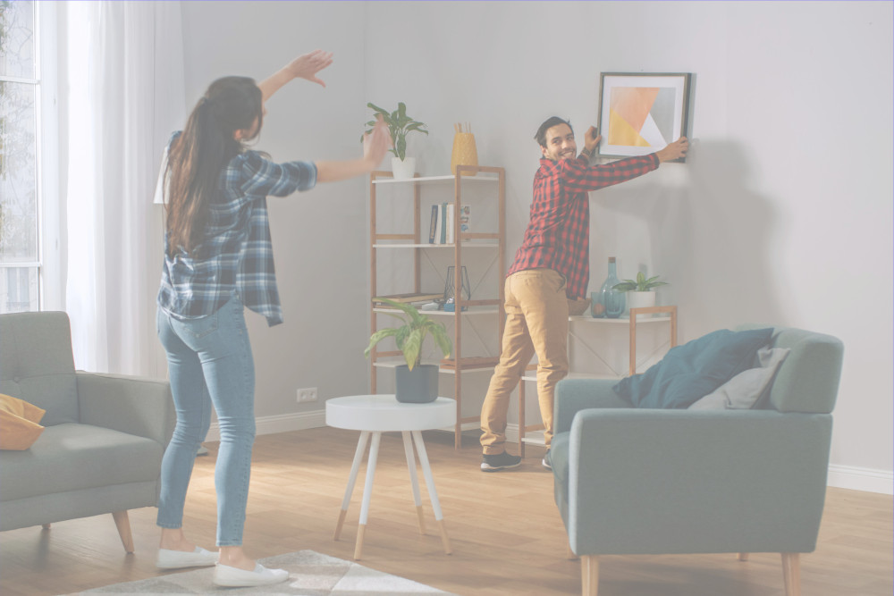 Couple adjusting the position of a painting on the wall